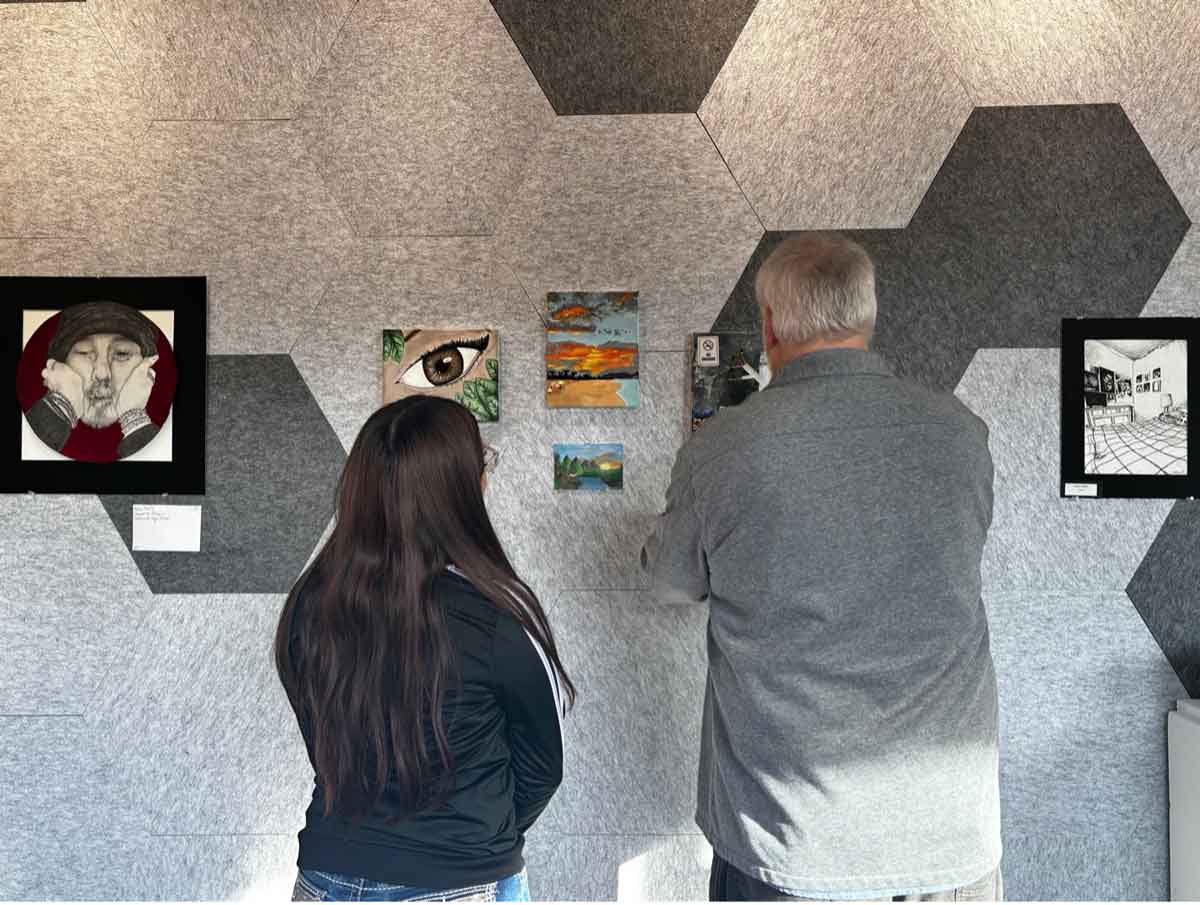Faculty member, Rob Robbins, and visitor setting up the Art Pop Up Exhibition for a chance to win a scholarship.