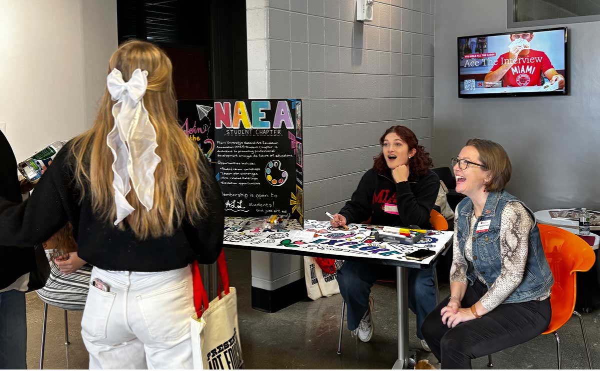 Members of the National Art Education Association student chapter, with students and faculty talking with visitors at their table.