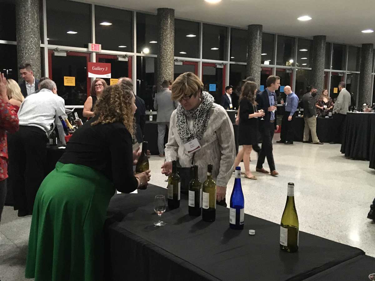 female attendee learning about wine from a wine vendor