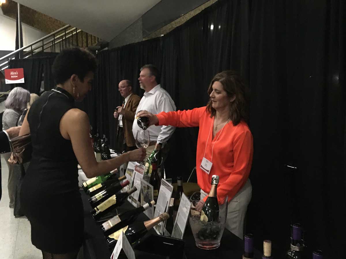 female wine vendor pouring wine into a female attendee's wine glass