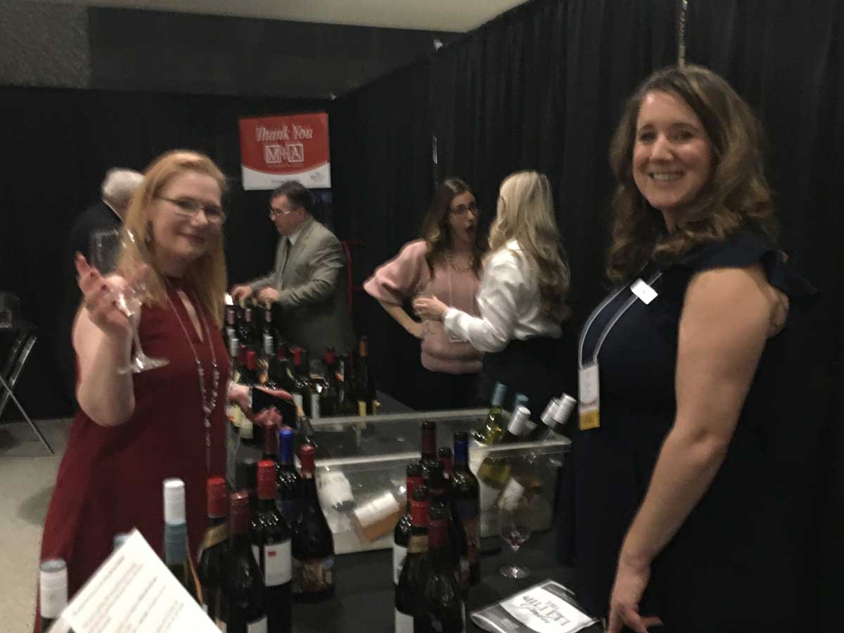 female attendee smiling with wine glass and wine vendor ready to pour wine