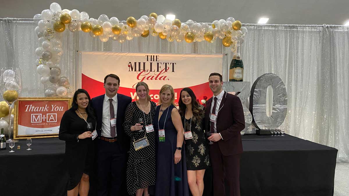 group posing in front of the event backdrop