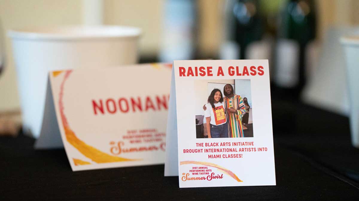  Image of a table card with the text "Raise a Glass" "The Black Arts Initiative brought international artists into Miami classes