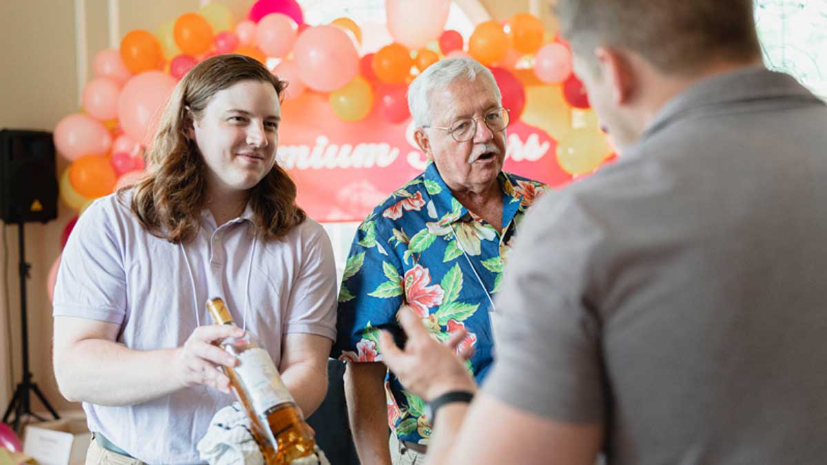 Jack Keegan and a volunteer discuss a premium pour vintage with an attendee