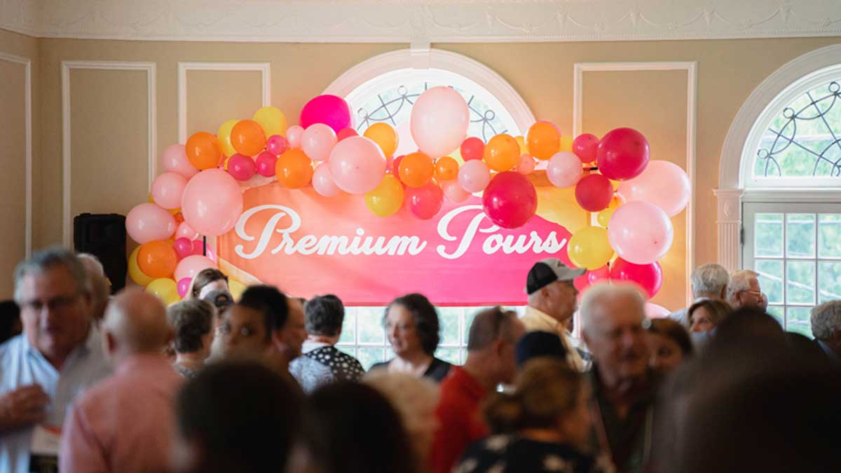 The Premium Pours area banner in sunset colors surrounded by balloons 