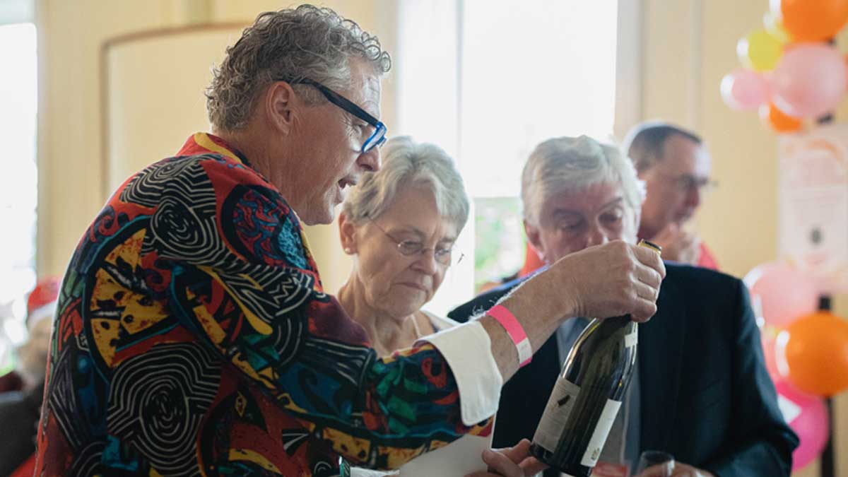  Longtime donor and sponsor Chris Adryan picks up a bottle to read the label
