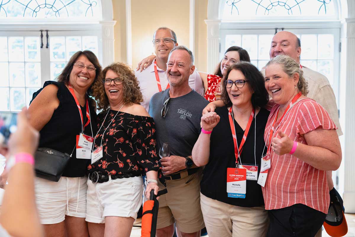 Miami University alumni smiling together at a wine tasting event in the Oxford Community Arts Center.