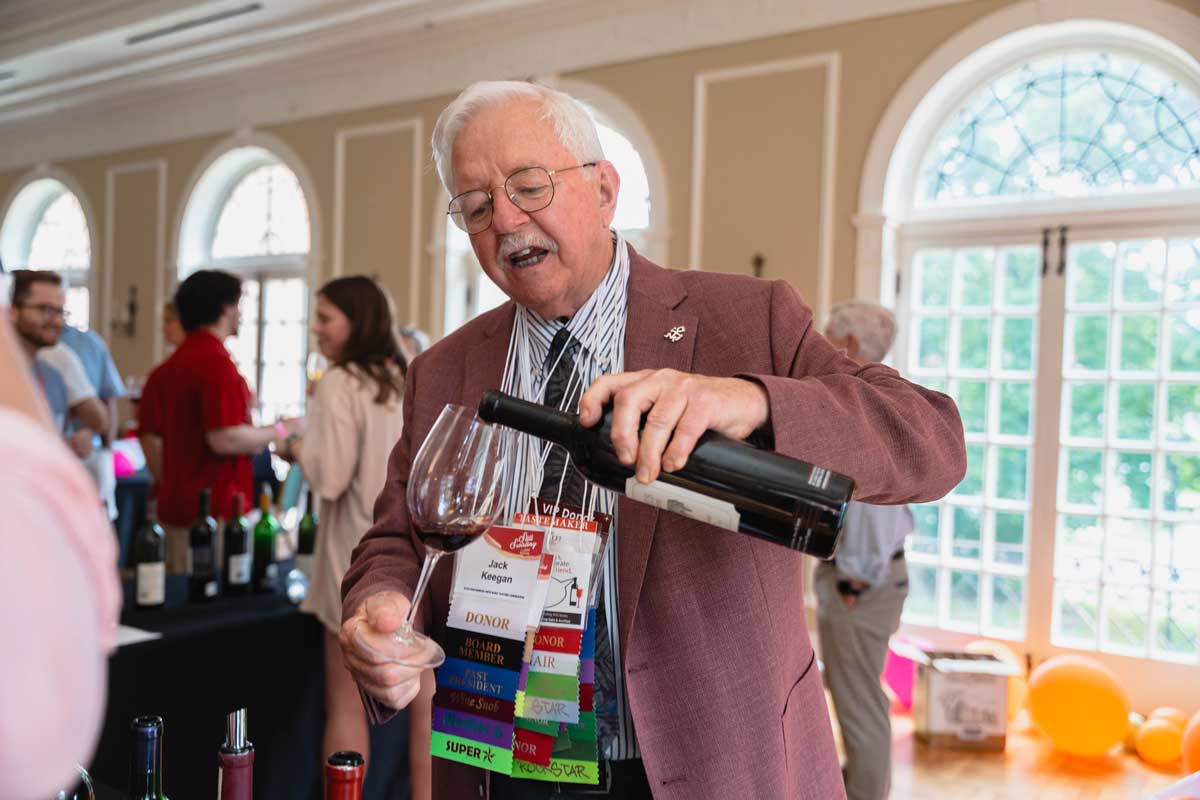 Jack Keegan pouring red wine during a wine tasting event in the Oxford Community Arts Center.