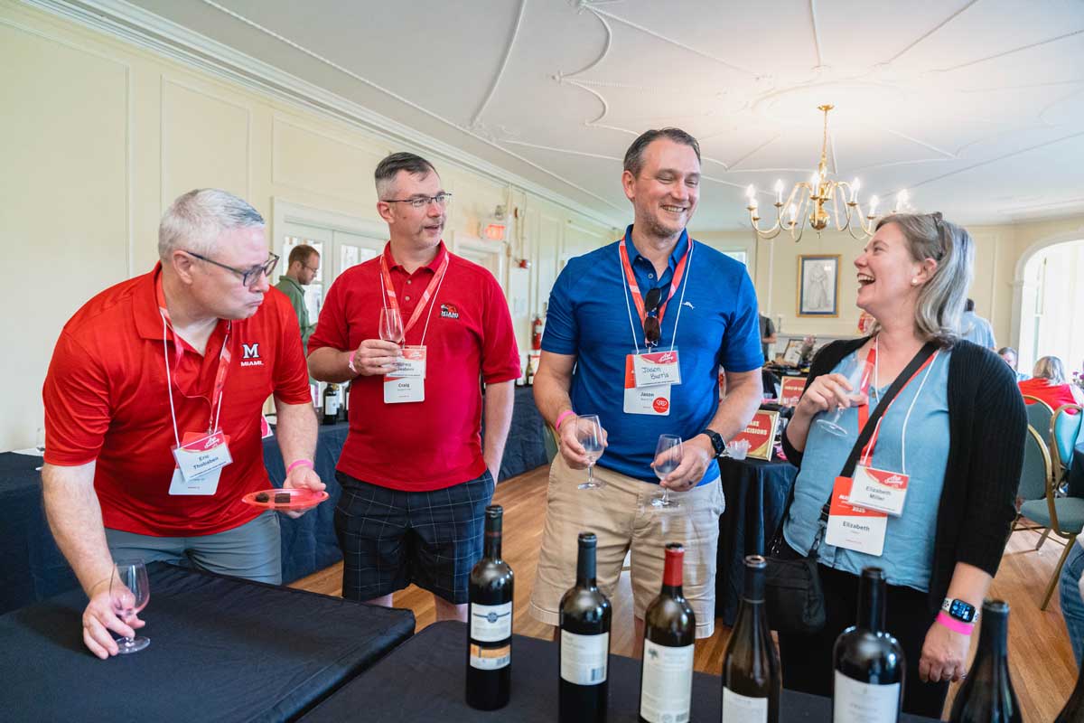 Participants laughing and networking over wine at a wine tasting event in the Oxford Community Arts Center.