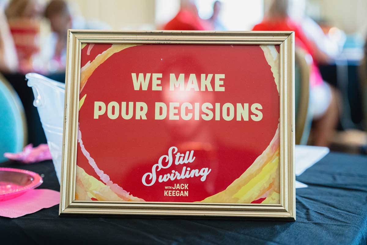 Sign reading We Make Pour Decisions at a Miami University alumni wine tasting event in the Oxford Community Arts Center.