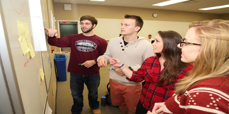 Group of students working on a project using a white board