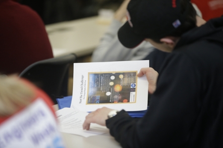 Male student wearing a hat looking at a start the trend challenge welcome packet
