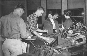 Black and white photo of students inspecting a piece of equipment