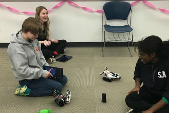 Girls Who Code play with a robot