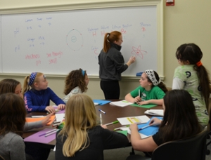 Volunteer teaches girl scouts about atoms
