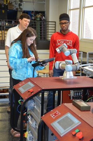 Robotics students work with a robot while an ECE faculty member supervises