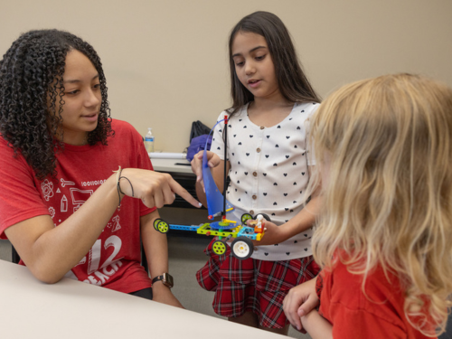 A female camp counselor interacts with two young female campers in the Art of Engineering summer camp.