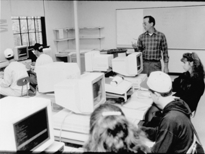 Black and white photo of students gathered around a computer