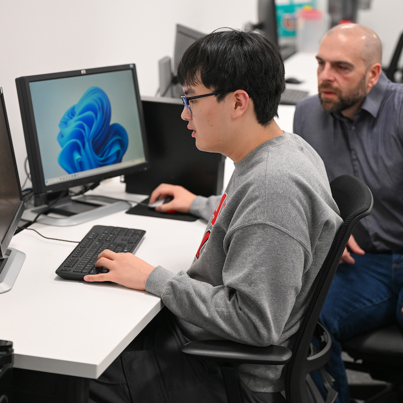 Professor specializing in machine learning works with a student in a computer lab