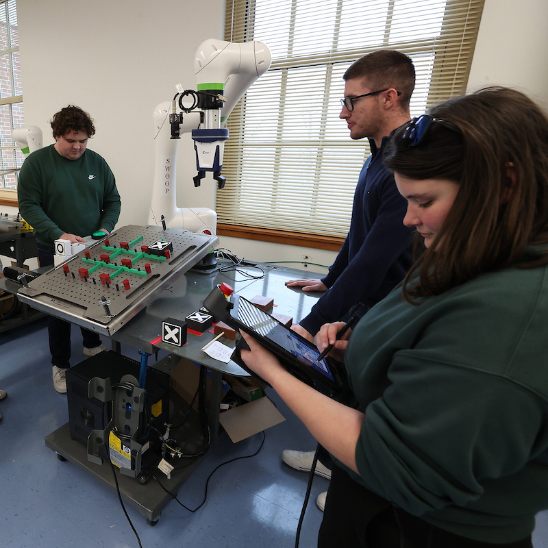 A group of electrical engineering students work on optimizing a tic tac toe playing robot.