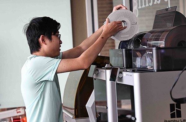 A graduate student works with a 3D printer as part of an electrical engineering master’s degree project.