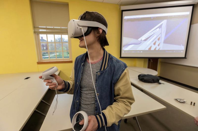 Male Computer Engineering student participating in the Senior Design Expo.  He is wearing a VR Headset.