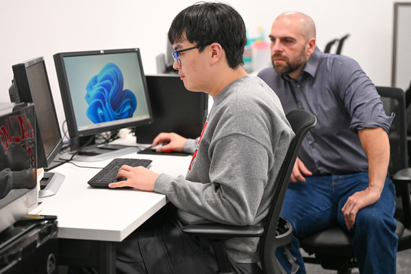 A graduate student works at an advanced computing setup working the field of generative AI
