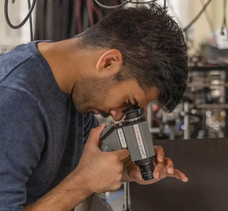 student looking with scope at materials on table