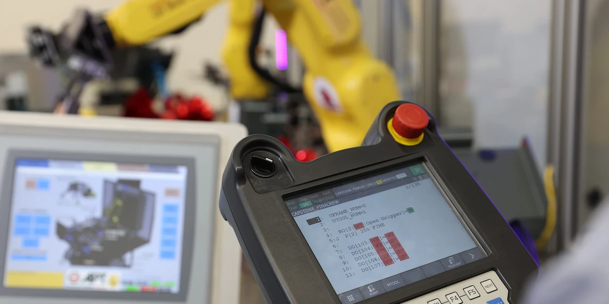 upclose of controller with data displayed with a laptop in background with machinery