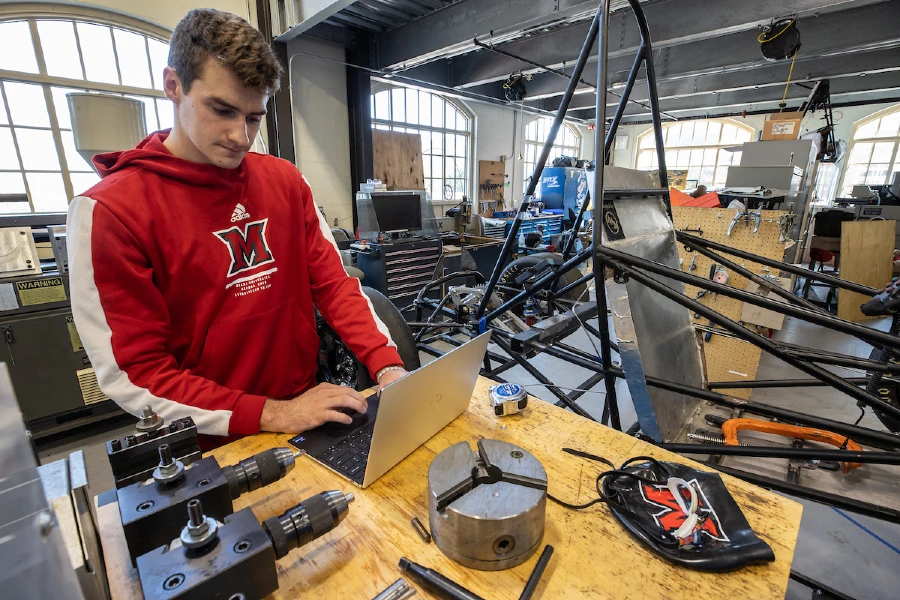 student working in lab with car in background