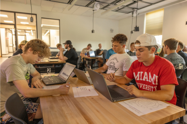 A group of male students work at laptops in the new First Year Experience Lab at Benton Hall