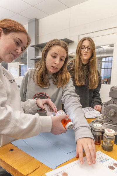 Three female CEC students review a color chart for their maintenance and reliability workshop.