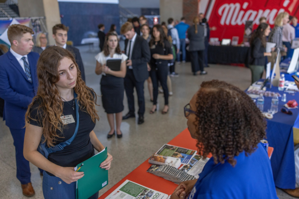 Female CEC student speaks with recruiter at STEM career fair.