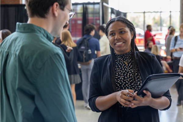 Female CEC student smiles and chats with professional recruiter at STEM career fair.