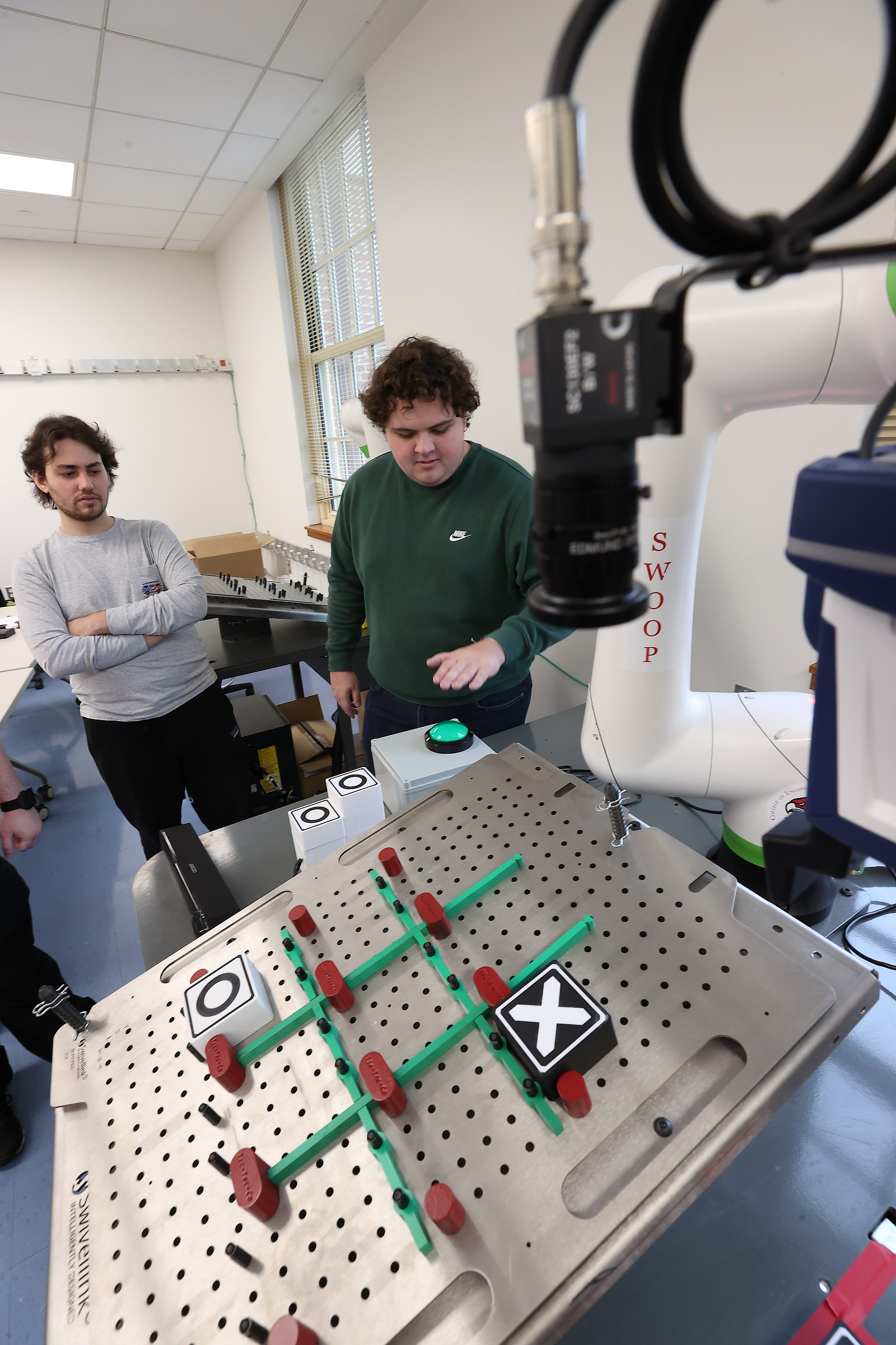 Carlo Buelvas and Parker Murphy consider their next move in a game of tic-tac-toe against a robot.