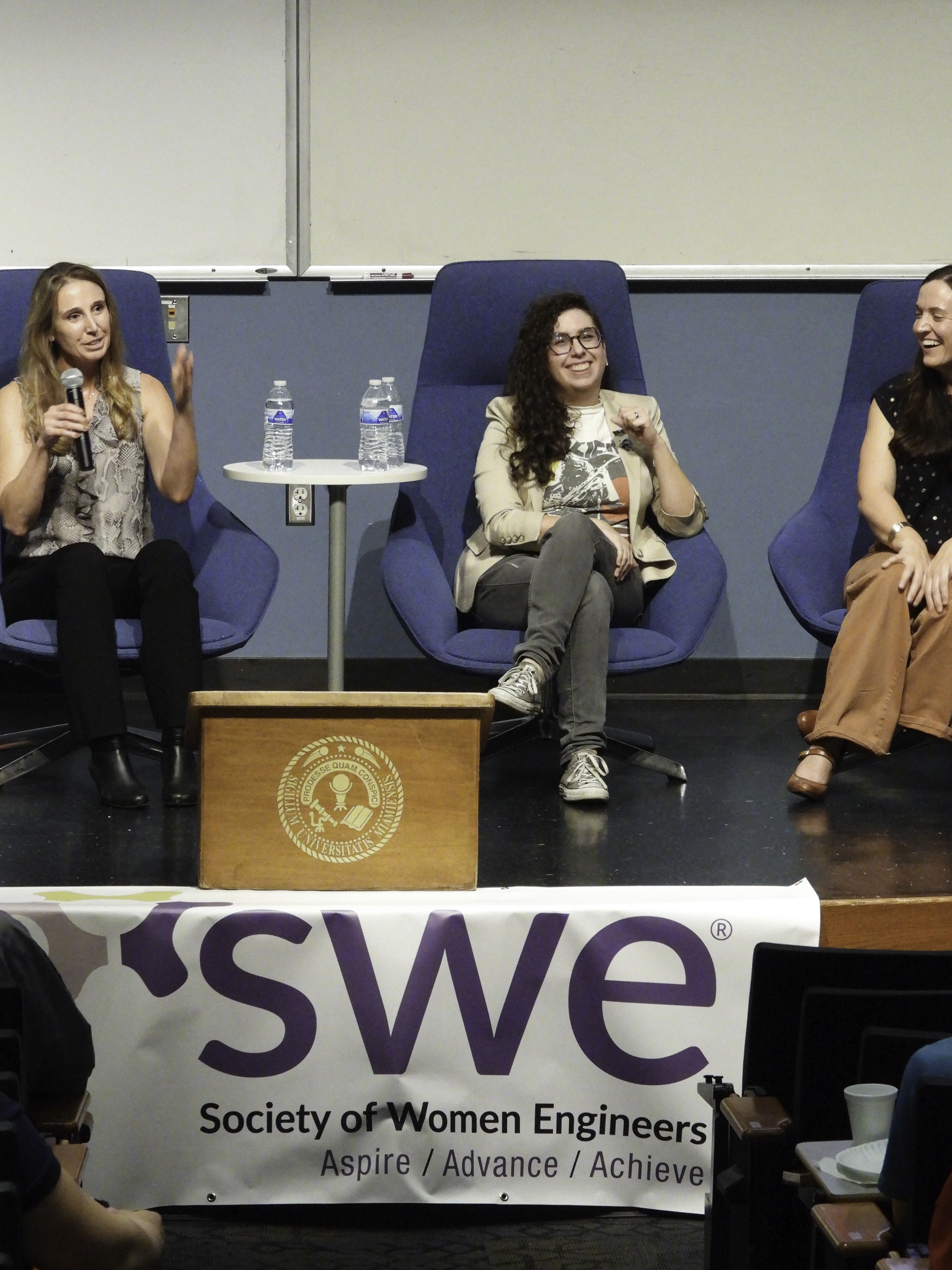 Female panelists smile and share insights on stage.