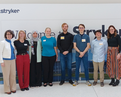 A group of biomedical engineering students in front of Stryker signage on an industry visit