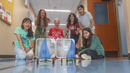 A group of middle school girls cheer in a Benton Hall corridor during a STEM summer camp.