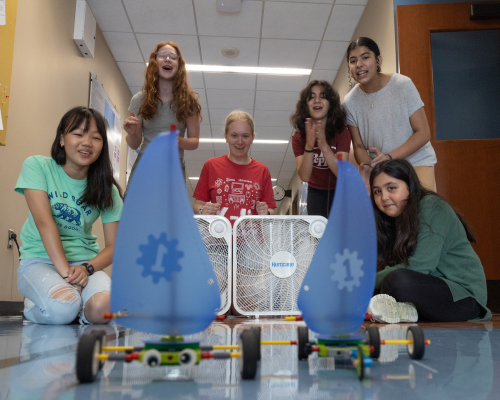 A group of middle school girls cheer in a Benton Hall corridor during a STEM summer camp.