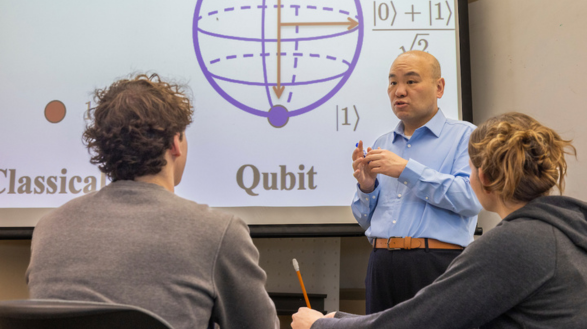 Liran Ma stands in front of a screen discussing computing concepts with students