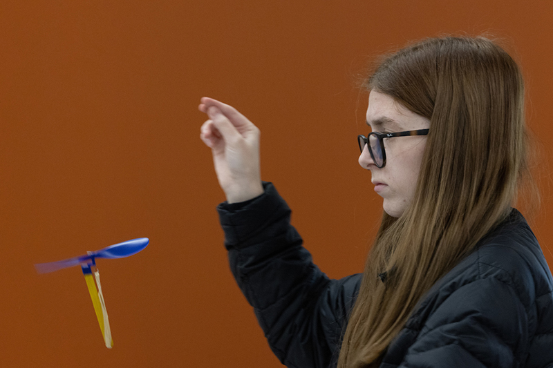 A girl works on a rubber-band powered helicopter.