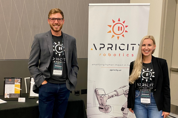 Aaron Crookes '16 stands in front of a sign for his company, Apricity Robotics