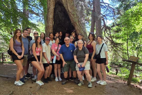 20 computer science students and two computer science faculty pose in a forest in Italy.