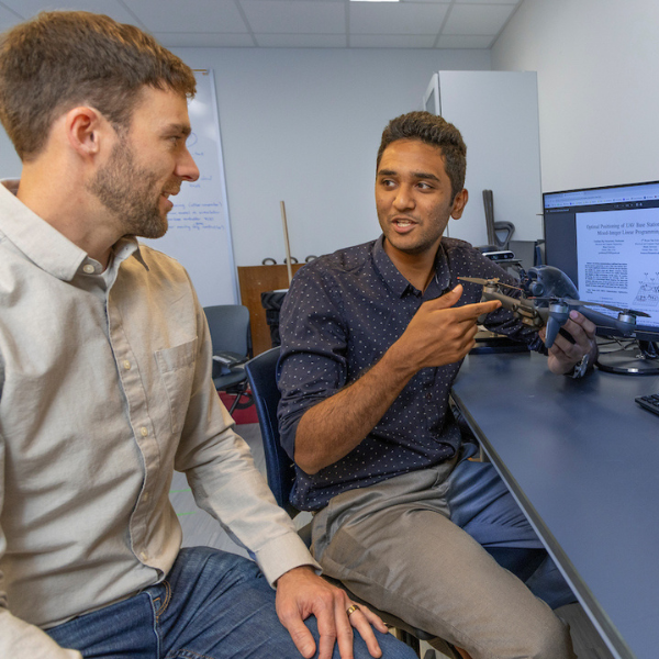 Graduate student with faculty member Bryan Van Scoy discuss a drone