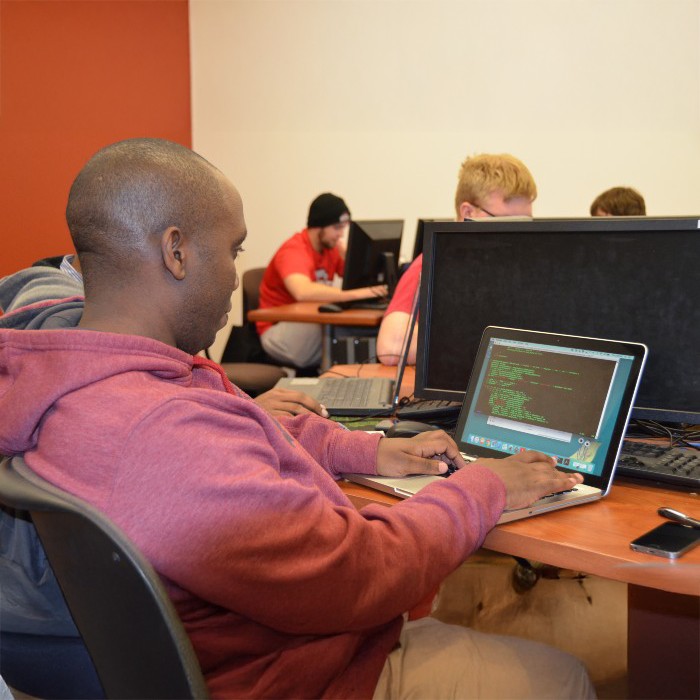 A student working at a laptop in a classroom.