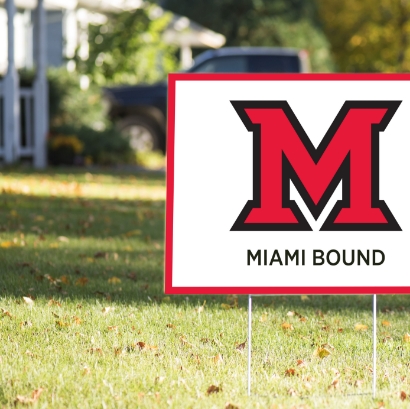 Yard sign standing in grass that says Miami Bound