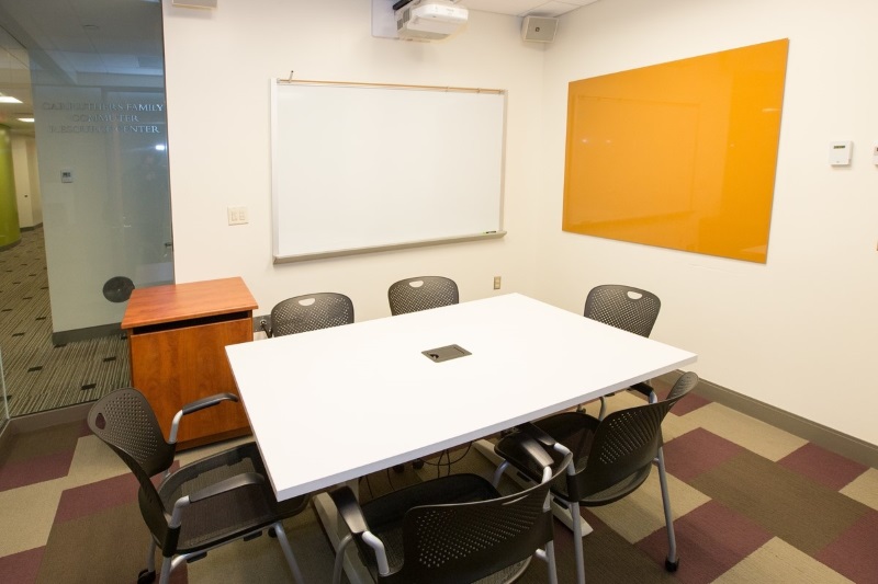 Small room with a square table seating 4, with a dry erase board on the wall. 