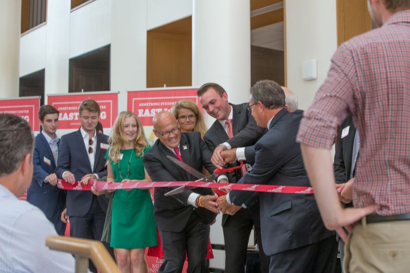 a group of people cutting a ribbon with large ceremonial scissors 
