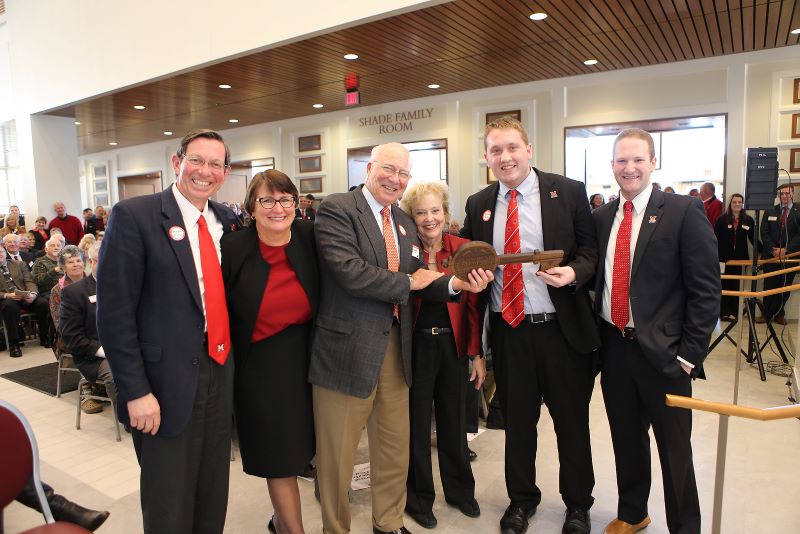 5 people holding a large wooden key in an atrium