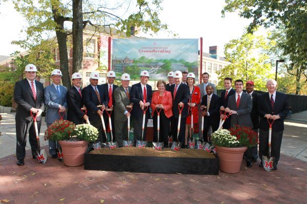 people standing with shovels in front of a rendering of the Armstrong Student Center